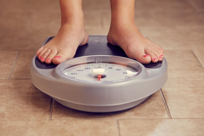 une paire de pieds féminins sur une balance de bain, tonique