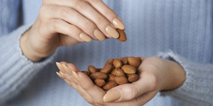 close up of woman holding handful of almonds