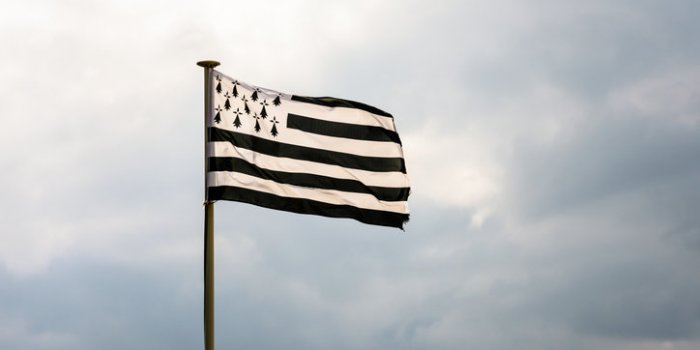 flag of brittany, named gwenn ha du in breton, flying in the wind at full mast against a stormy sky