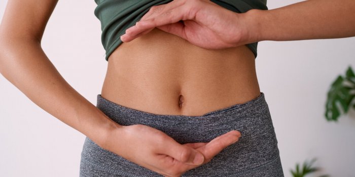close up of a young multi-ethnic woman's stomach cupped by her hands high quality photo