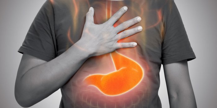 a man burning sensation in chest from acid reflux on gray background
