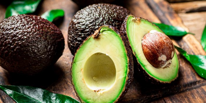 halves of fresh avocado on a cutting board on a wooden background high quality photo