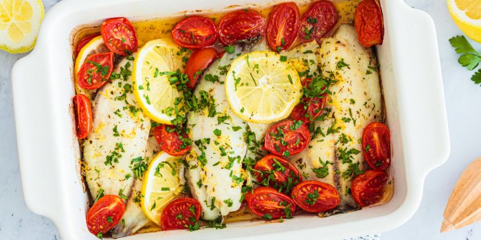 baked cod fillet with cherry tomatoes and butter, top view healthy diet recipe