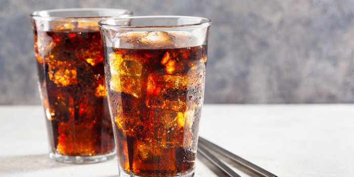 glass of cold cola soft drink with ice on wooden background