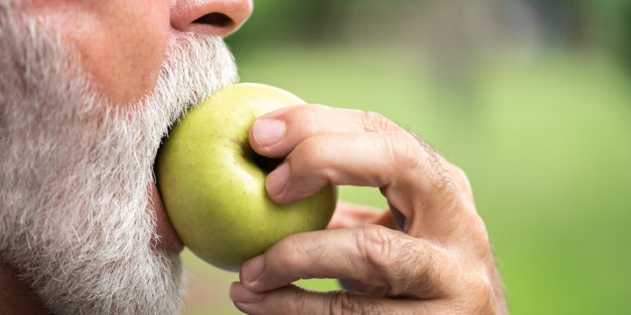 senior sportsman eating green apple