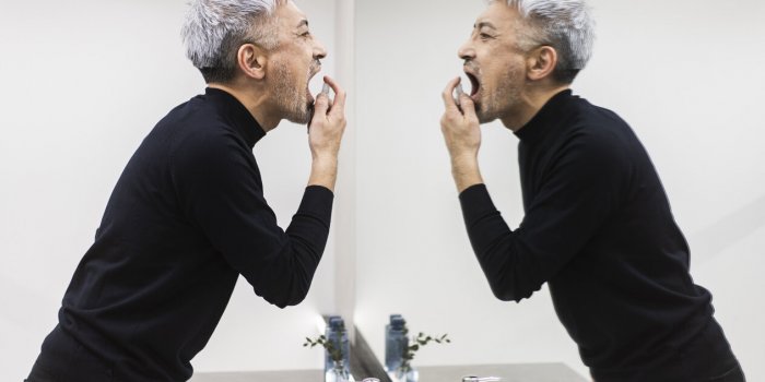 a middle-aged man is taking care of his throat with a throat medicine