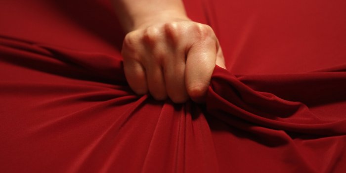 woman hand passionately squeezes red bed sheet love concept