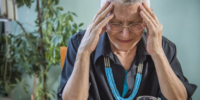 senior elderly lady having a strong and throbbing headache