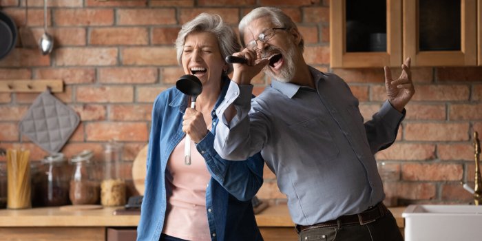 happy senior husband and wife have fun sing in kitchen appliances cooking together at home overjoyed mature grey-haired c...