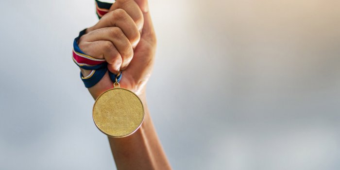 hand holding gold medal on sky background, the winner and successful concept