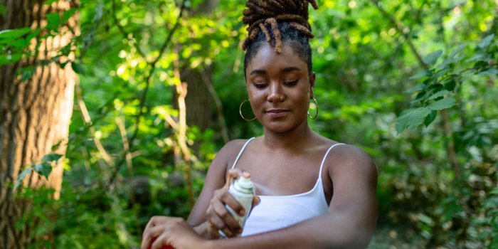 woman applying insect repellent against mosquito and tick on her arms during hike in nature skin protection against insec...