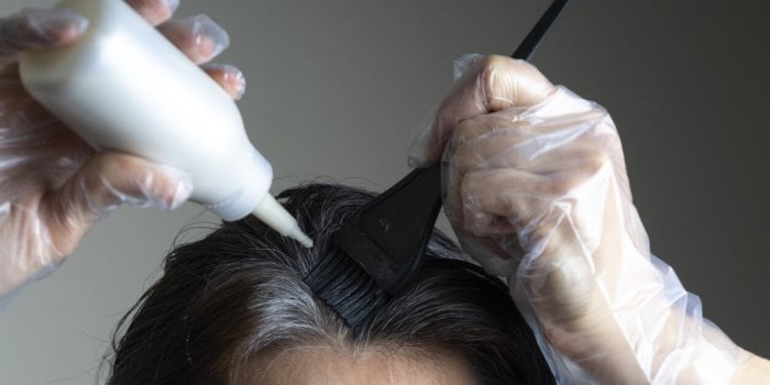 closeup woman hands dyeing hair using black brush middle age woman colouring dark hair with gray roots at home