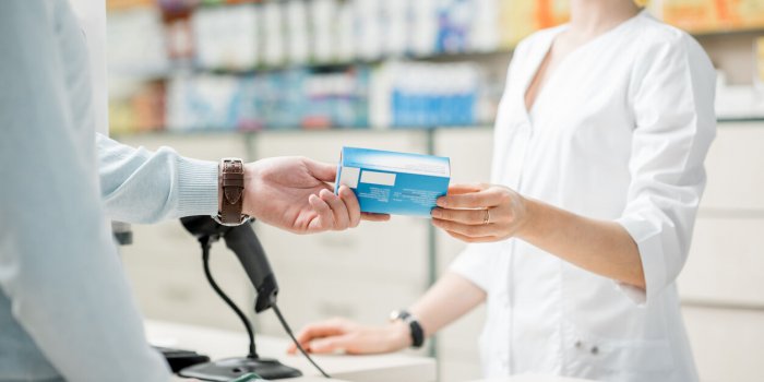 pharmacist giving a box with medication for the client in pharmacist close-up view focused on the hands