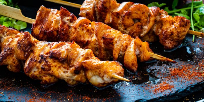 shashlik - grilled meat and vegetables on stone plate on wooden table