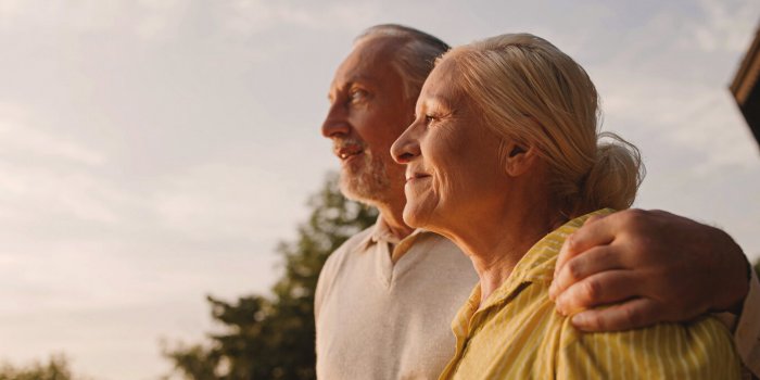 smiling aged couple hugging outdoors, enjoying city view at sunset, family love