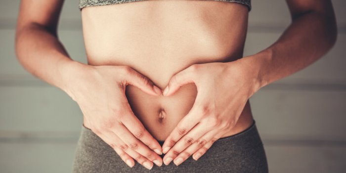 cropped image of slim afro american girl in sportswear showing heart on her stomach