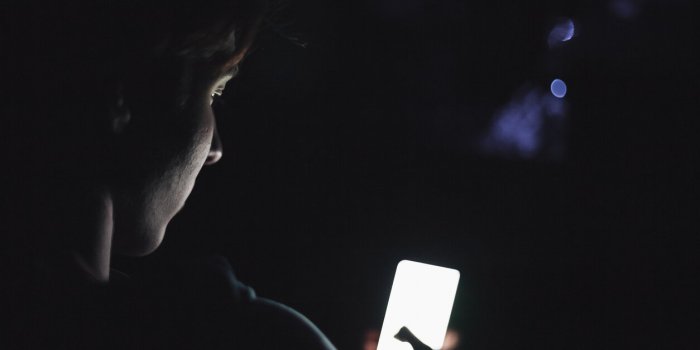 teenage boy using smart phone in the dark, focus on face