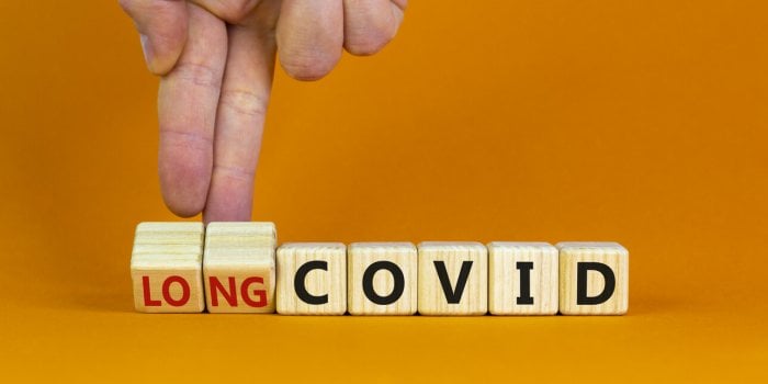 long covid symbol doctor turnes wooden cubes and changes words 'covid' to 'long covid' beautiful orange background, copy ...