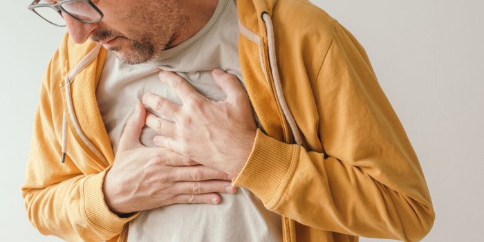 aching chest, adult male with painful grimace pressing the upper abdomen with his hands to ease pain, pericarditis concept