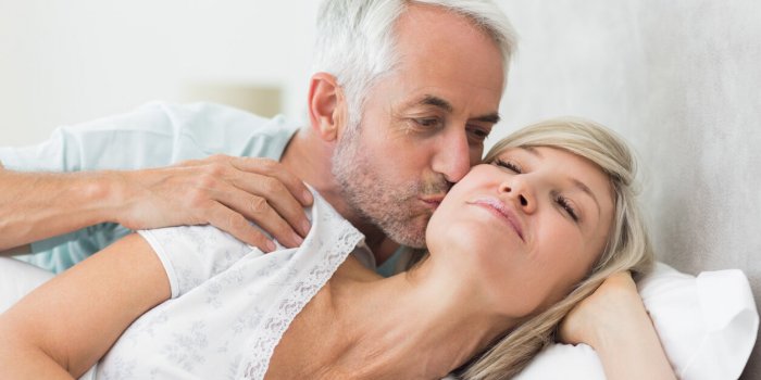 closeup of a mature man kissing womans cheek in bed at the home